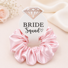 Load image into Gallery viewer, Pink Bride Squad satin scrunchie with diamond tag, styled as a bridal party accessory for bridesmaid proposal gifts.