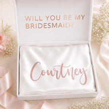 Load image into Gallery viewer, Personalised white satin bridesmaid robe with name decal, styled in a bridal proposal box for wedding morning gifts and bridal party keepsakes.