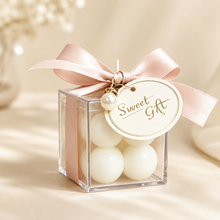 Load image into Gallery viewer, Mini clear sweet gift box with blush ribbon and pearl charm, styled as a bridal favour for bridesmaid proposal bags.