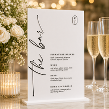 Load image into Gallery viewer, Custom white acrylic wedding bar menu sign with black vinyl text and wooden base styled with champagne glasses, candles and white florals.
