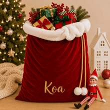 Load image into Gallery viewer, Personalised extra large red velvet Santa sack with custom name displayed under a Christmas tree ready for Christmas gifts.
