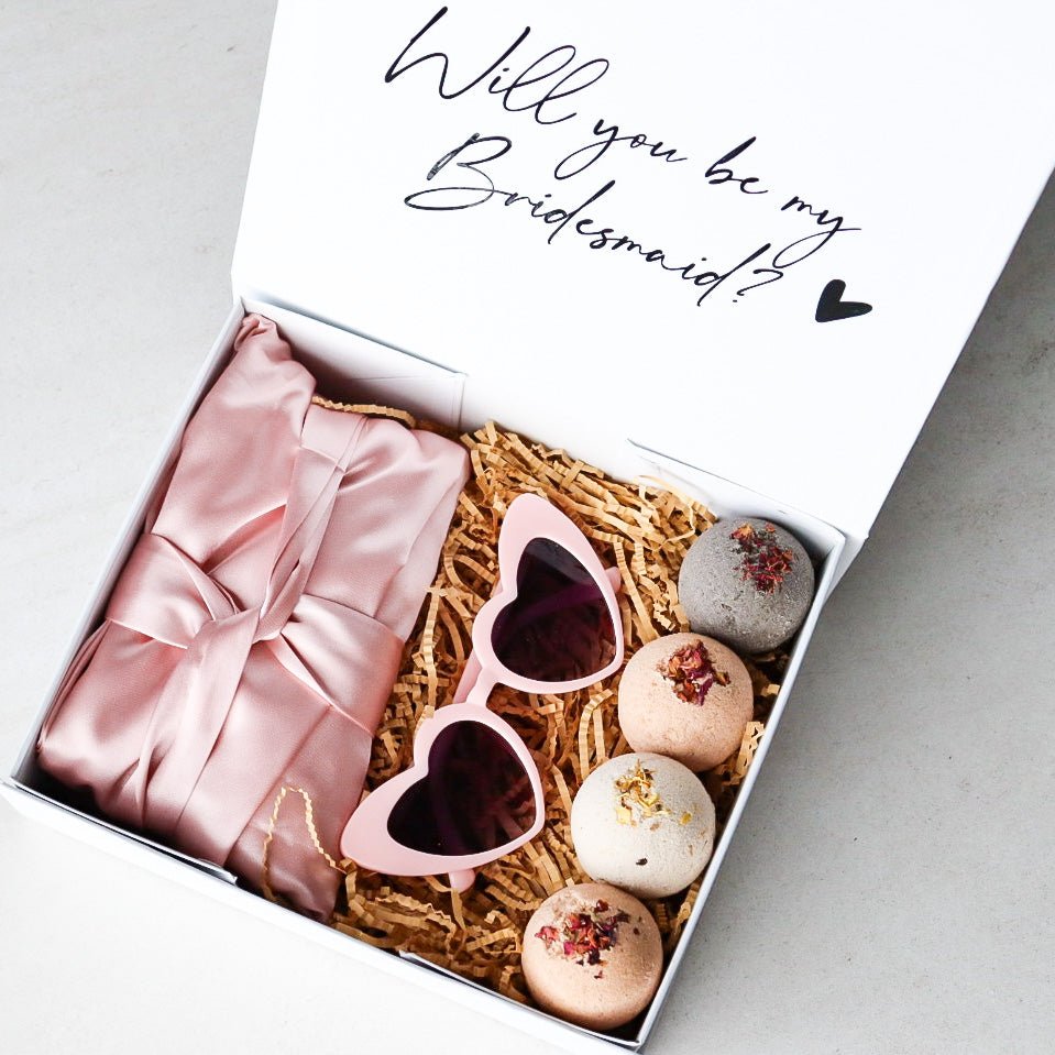 Elegant personalised bridesmaid proposal box with heart-shaped glasses, satin robe, handmade bath bombs, and a custom gift box with ribbon.